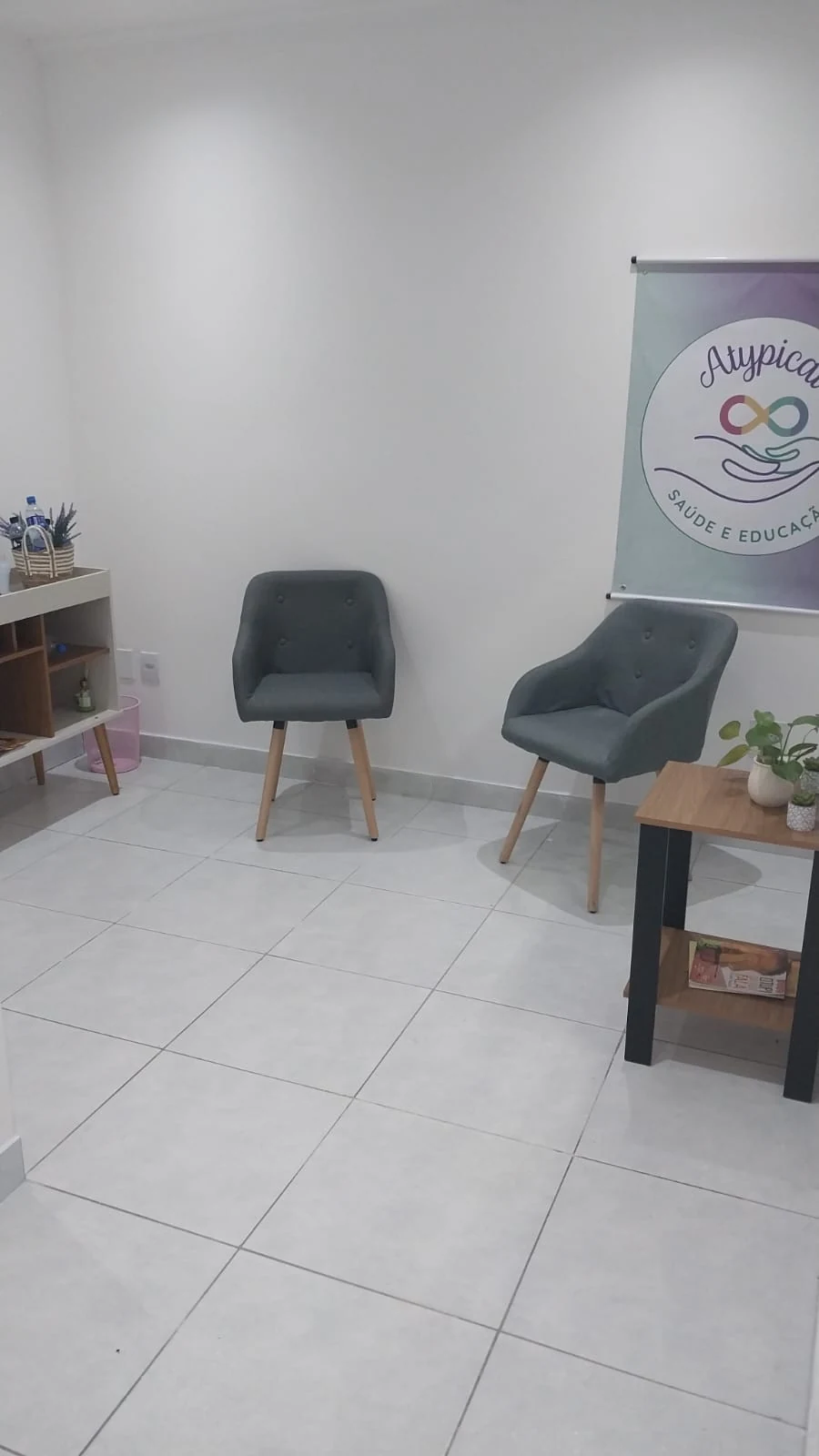 Sala da Atypical com poltronas e a marca da clínica na parede